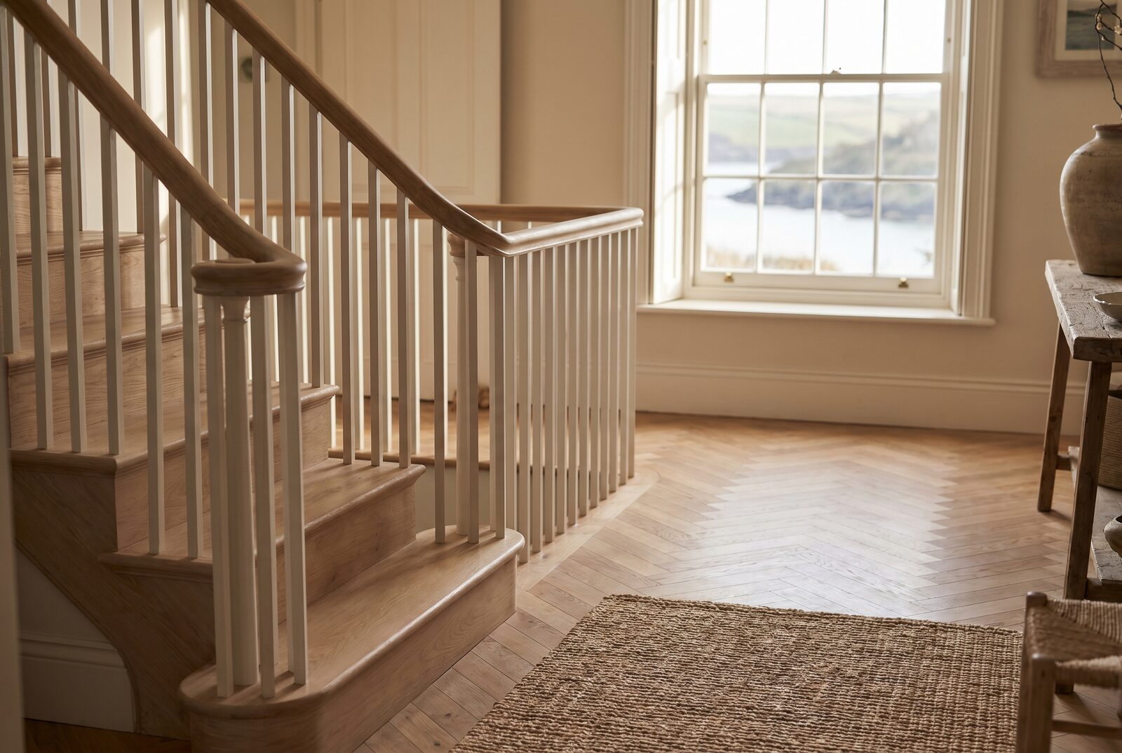 Pale oak staircase descending to a restored herringbone hallway