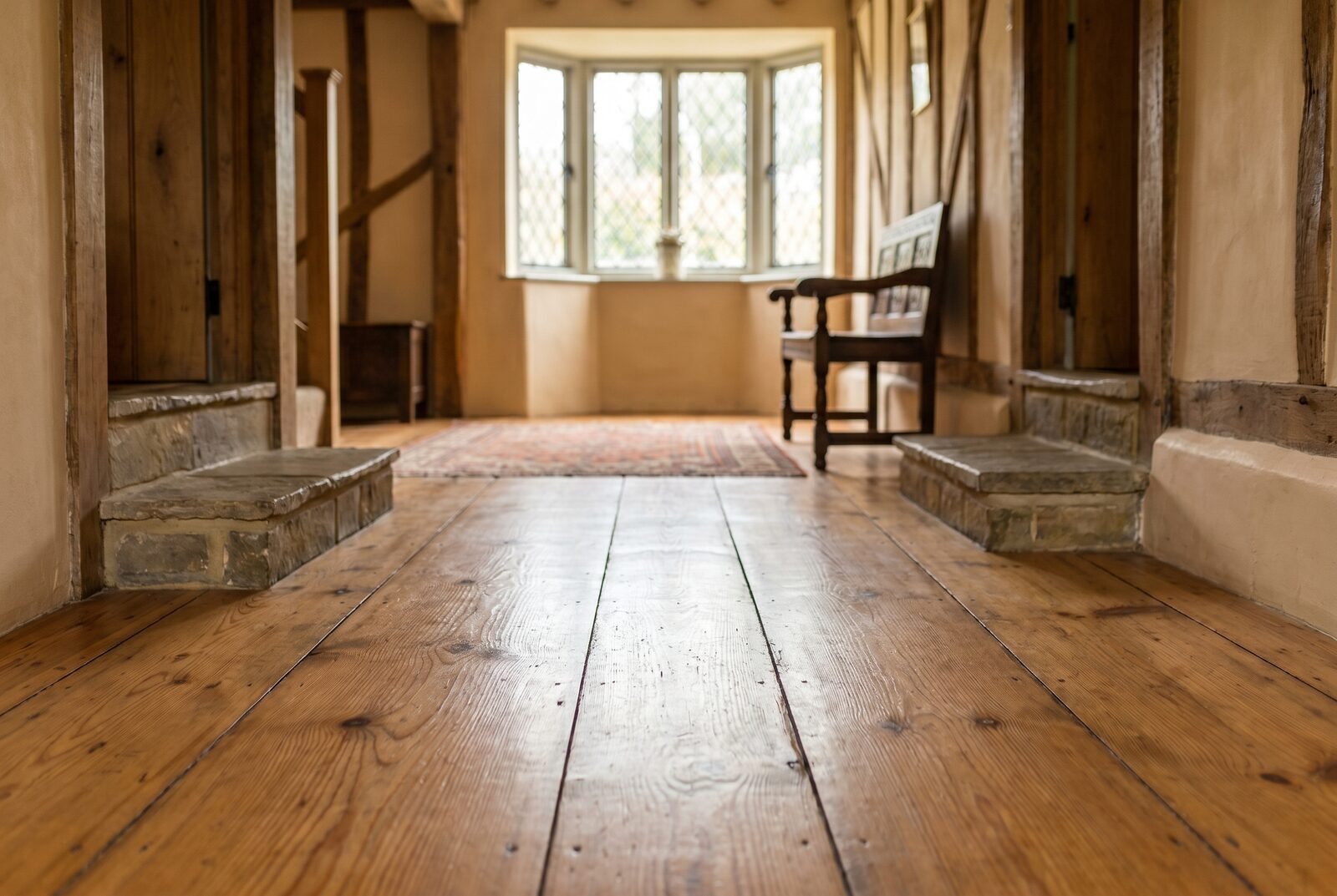 Restored wide pine boards finished to a warm hand-buffed satin in a beamed farmhouse