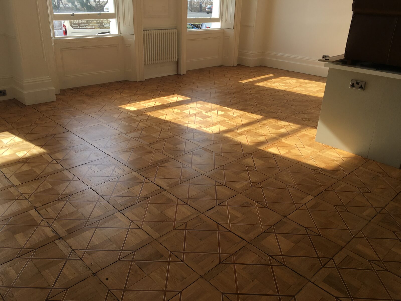 Restored oak parquet block flooring in an intricate geometric panel pattern
