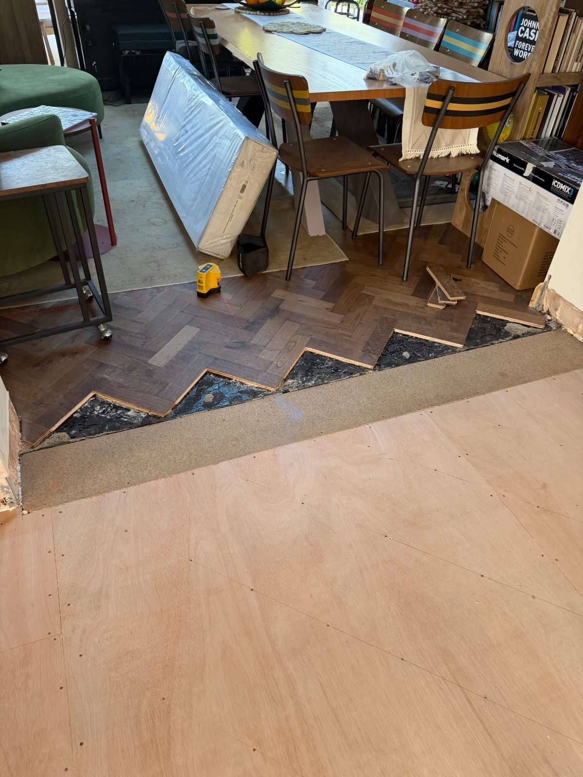Oak herringbone blocks lifted at a threshold with a laser level set out on a Summerley Estate floor