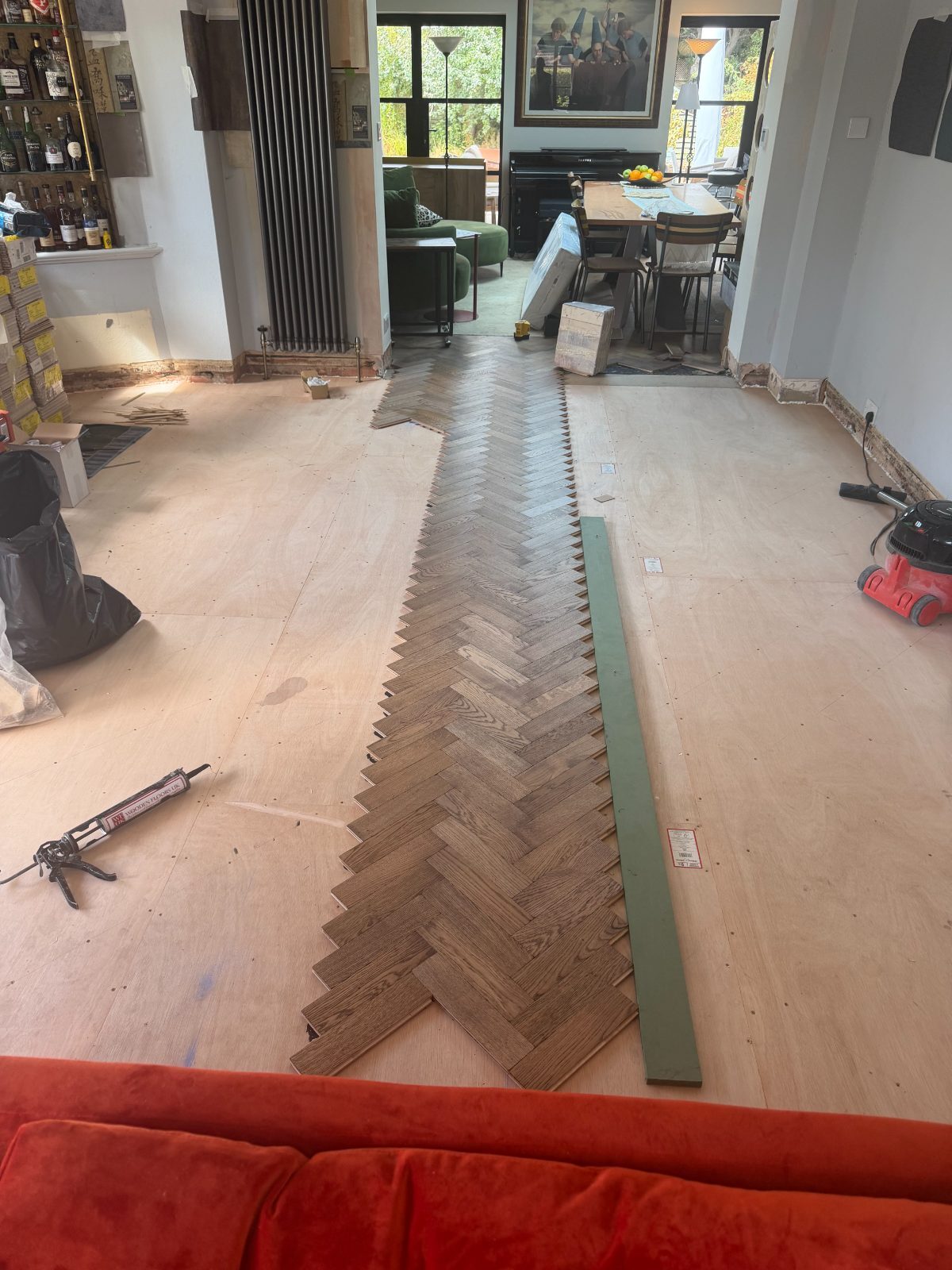 New light oak herringbone parquet being laid across a plywood subfloor in a Summerley Estate home