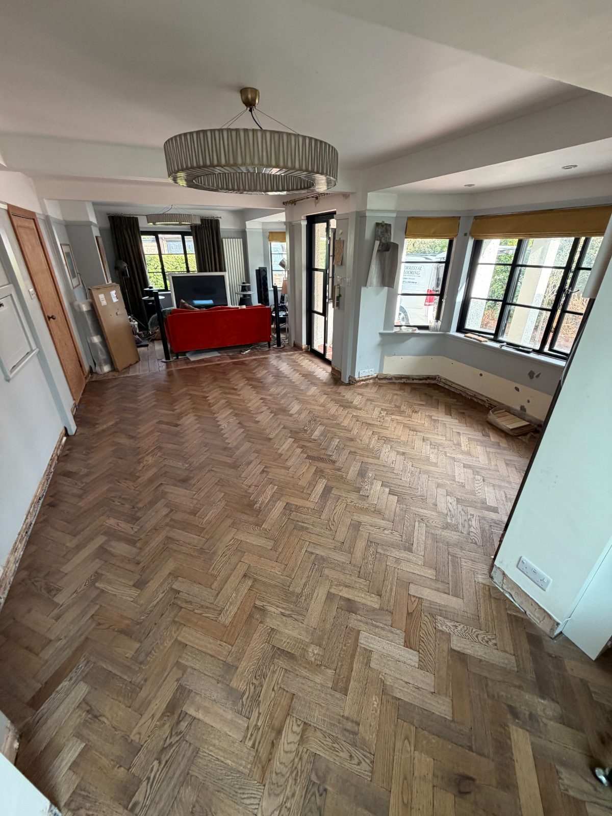 Finished oak herringbone parquet in a Summerley Estate home, sanded to a warm natural tone beside the bay window