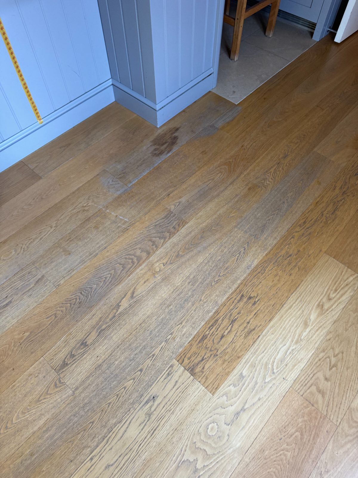Close detail of characterful engineered oak plank flooring being refinished beside a grey painted kitchen island in a Bosham Hoe home