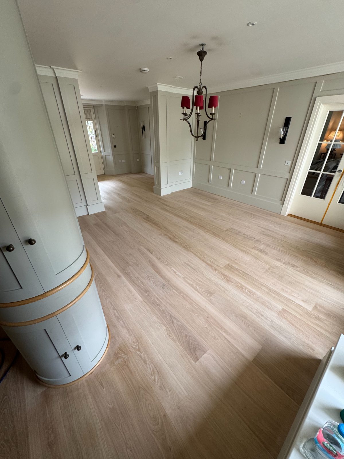 Pale limed engineered oak plank floor in a sage-panelled reception room with a chandelier, a restored Bosham Hoe floor