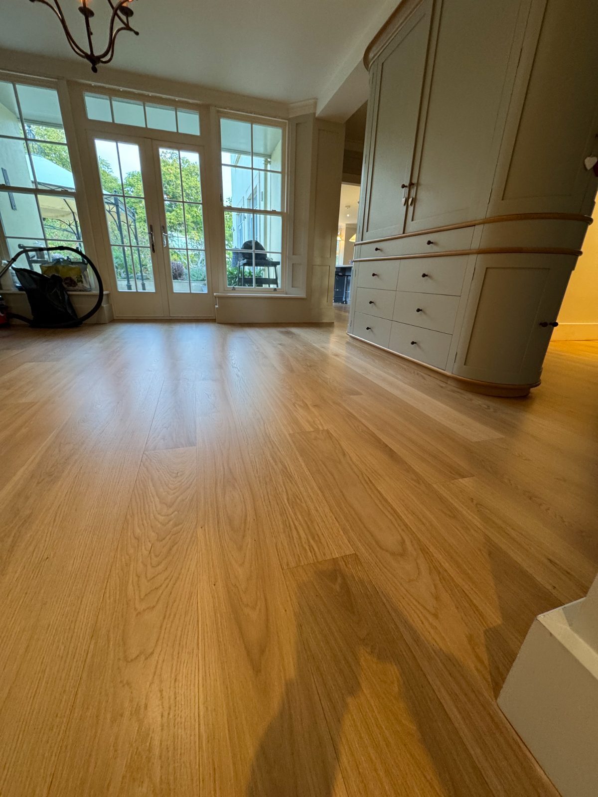 Restored engineered oak plank flooring in warm honey tones running to French garden doors in a Bosham Hoe home