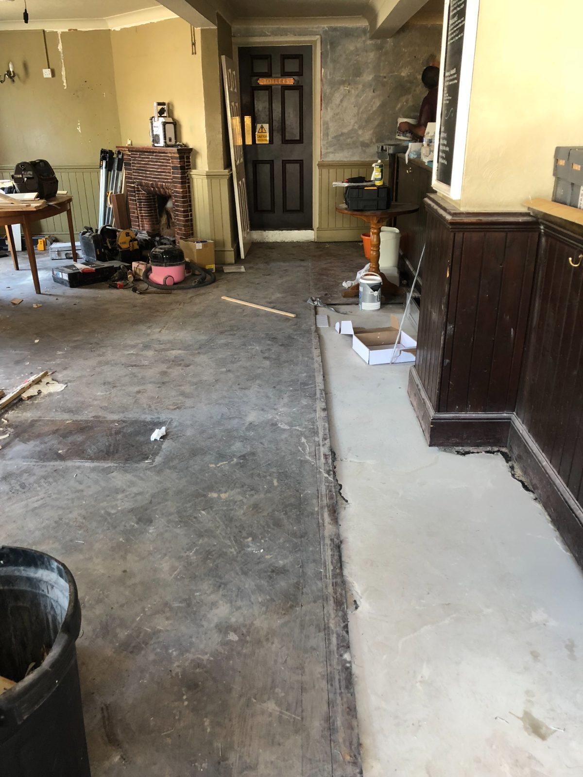 The bar of The Thatched House pub in Felpham stripped back to bare subfloor and fresh screed, mid wood-block restoration