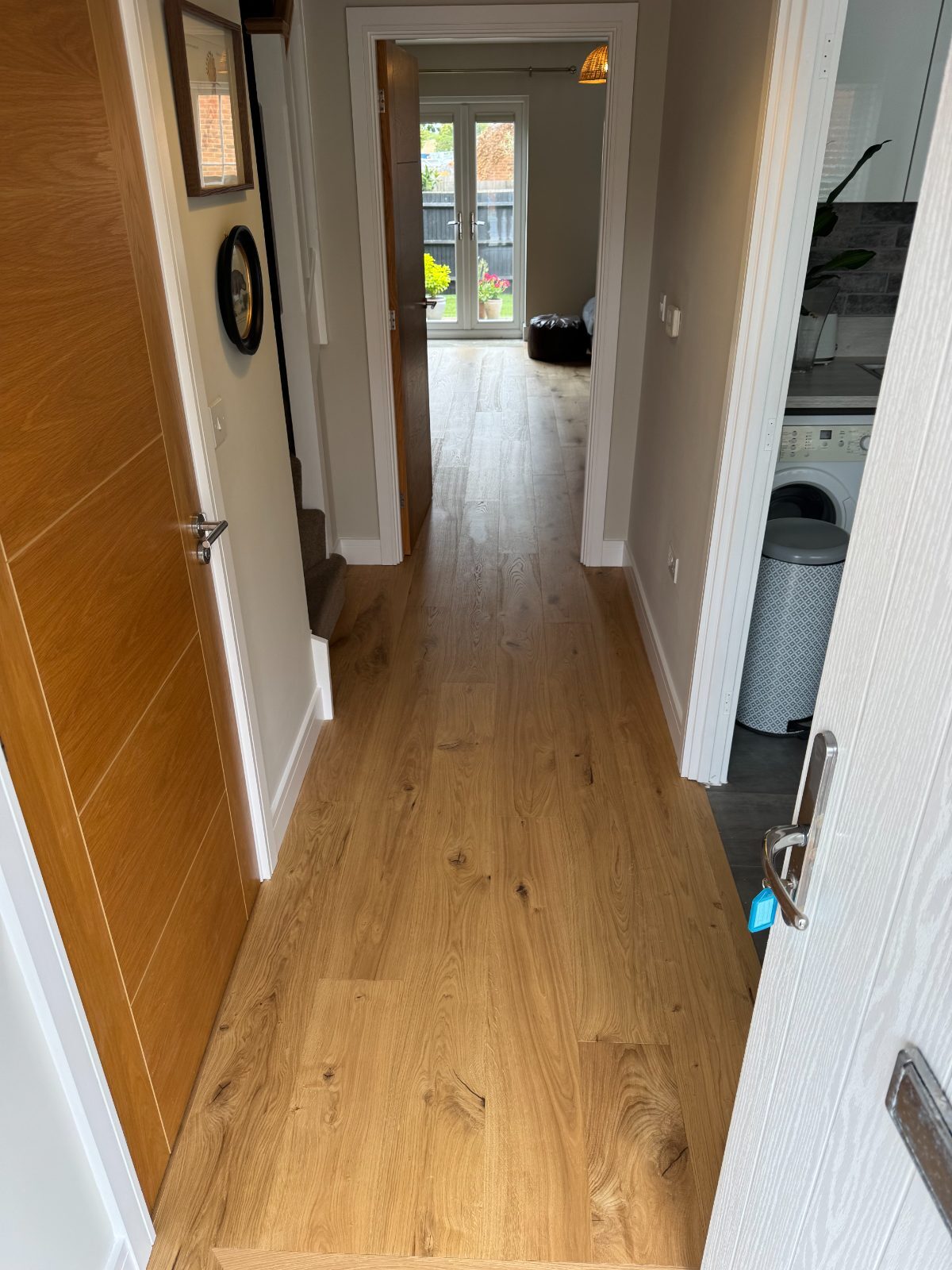 Honey-toned engineered oak boards running the length of a Bognor Regis hallway through to a garden room