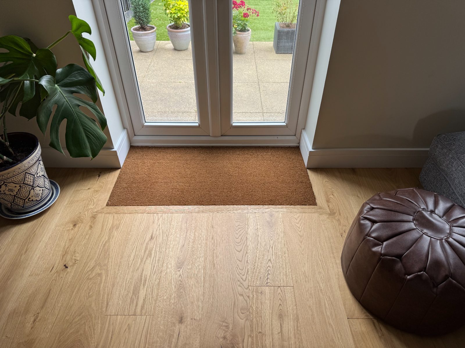 Pale whitewashed-oak engineered boards with a coir mat set flush into the floor by the garden doors of a Bognor Regis home