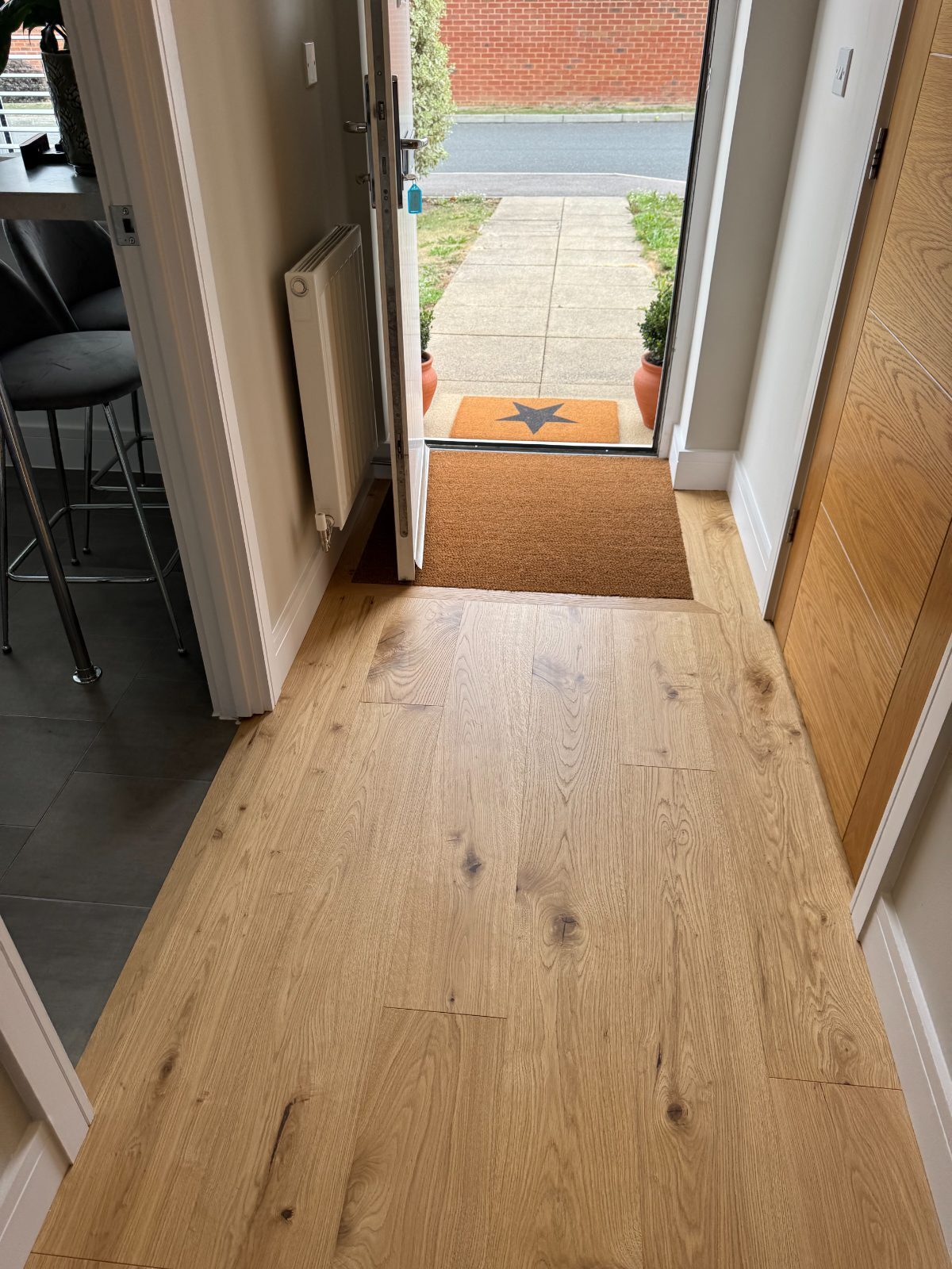 Honey-toned engineered oak flooring in a Bognor Regis front entrance hall with the front door open to the street