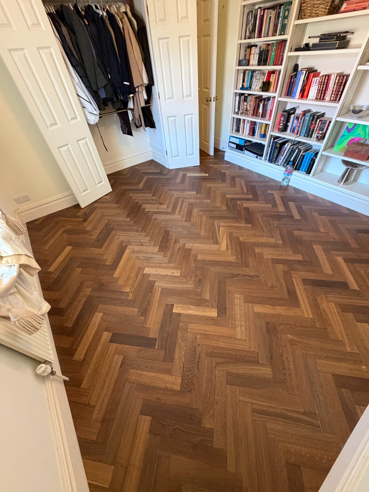 Finished oak herringbone parquet running from a dressing room with an open wardrobe into a library at Burton House